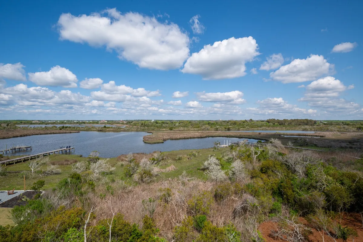 A peaceful water view scene with calm surface, distant greenery, and gentle clouds overhead. The natural landscape suggests a place for boating, birdwatching, or simply enjoying the tranquility of the island’s surroundings.