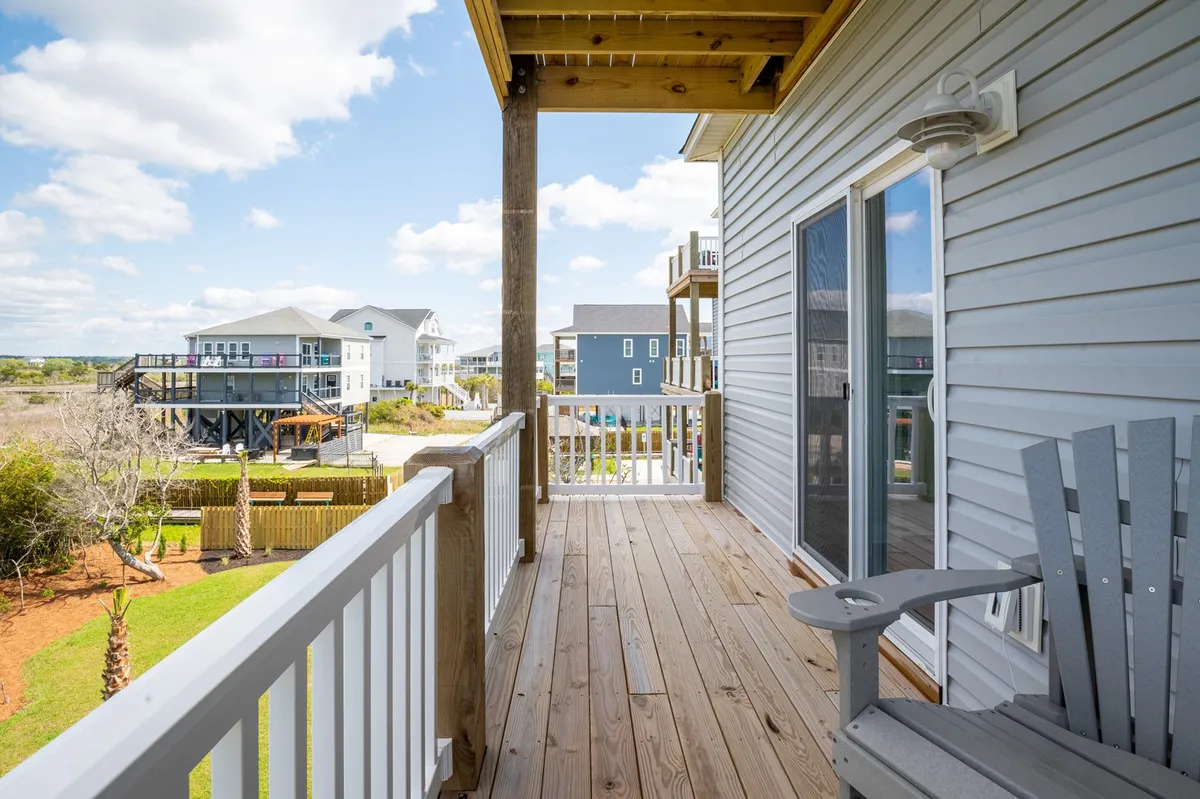 This image features a wooden deck that overlooks the landscape with adjoining houses, evoking a sense of spaciousness and privacy. The tranquil mood is enhanced by the open view and the inviting setting for relaxation or socializing outdoors.