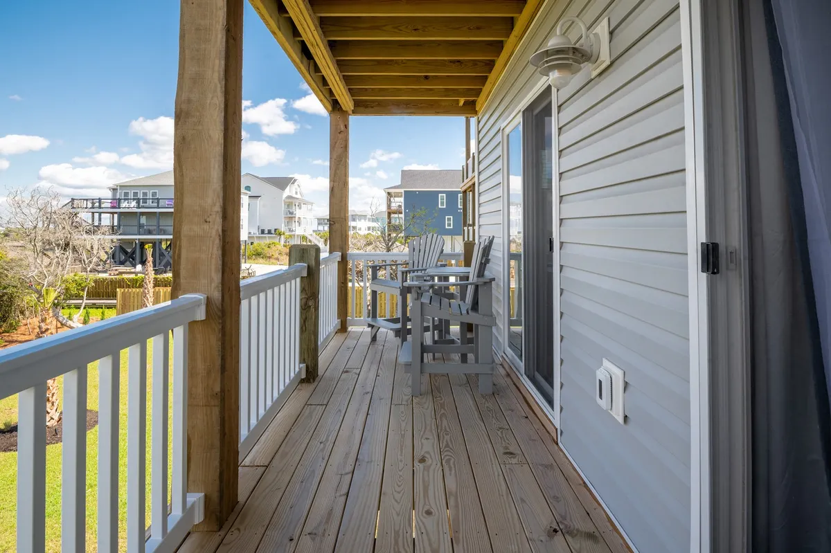 An inviting exterior image of a deck with railings, outdoor chairs, and a view of neighboring houses. The relaxed atmosphere is set for sipping coffee, reading, or hosting casual gatherings as the sun sets.