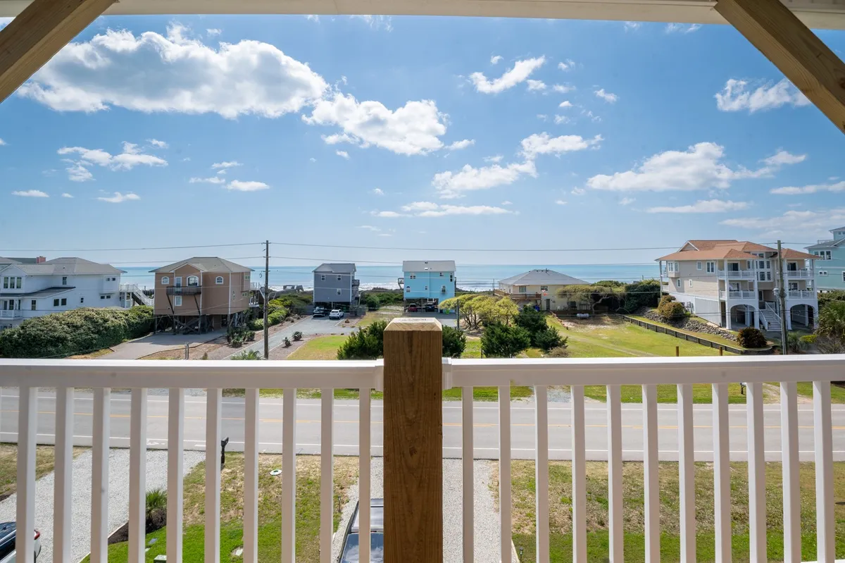 A breathtaking ocean view dominates this scene, capturing the essence of a luxurious, private escape. The clouds and neighboring houses are visible, but the focus remains on the vastness and serenity of the ocean beyond.