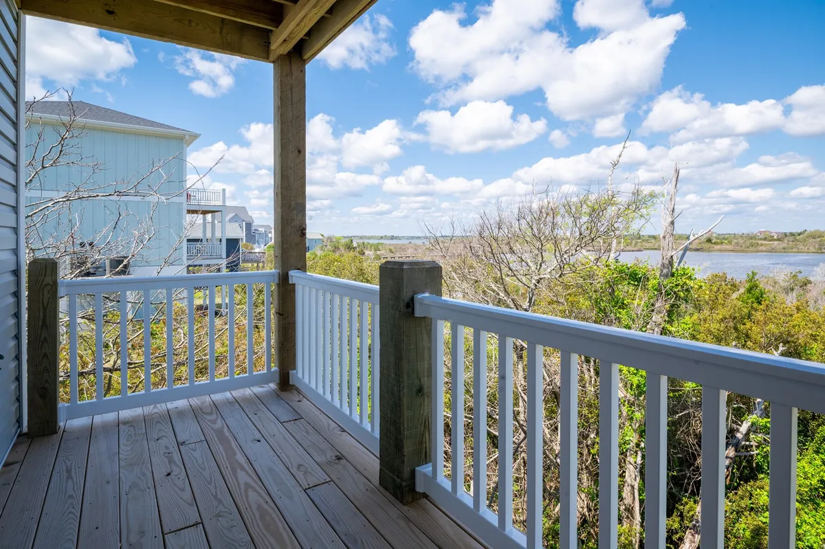 A private balcony with a wooden floor and railing, overlooking water and open sky. The space is peaceful, perfect for enjoying morning coffee or a sunset nightcap, with distant water views enhancing the sense of seclusion.