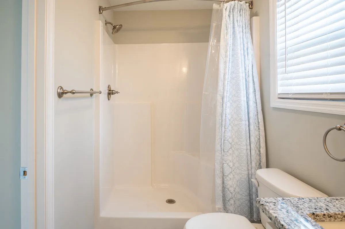A spa-inspired bathroom with a glass-enclosed shower area, modern sink with countertop, and ample natural light, evoking a serene and refreshing experience for guests.