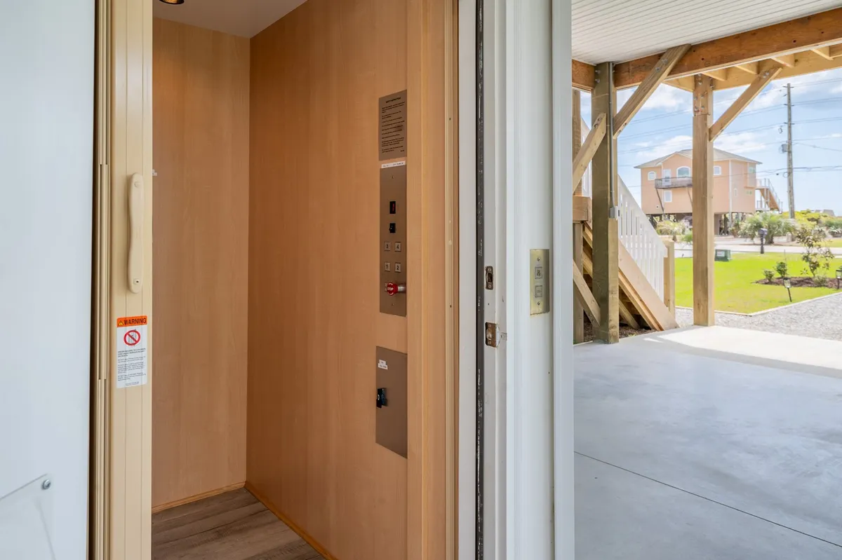The interior of the home’s elevator is shown with an open door and control panel, highlighting its ease of use. The welcoming, practical mood reinforces its role in comfortable arrivals with luggage or groceries.